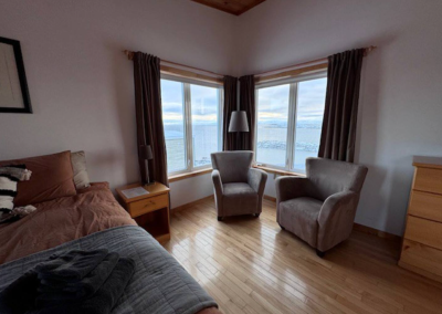Indoor sitting area in Bedroom 2 at Stay by the Sea B&B, Iqaluit, featuring sofa chairs beside large windows overlooking Frobisher Bay.