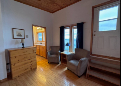 Indoor sitting area in Bedroom 1 at Stay by the Sea B&B in Iqaluit, featuring chairs by a window with a scenic ocean view of Frobisher Bay